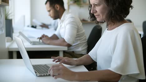 Side-view-of-focused-Caucasian-woman-working-with-laptop